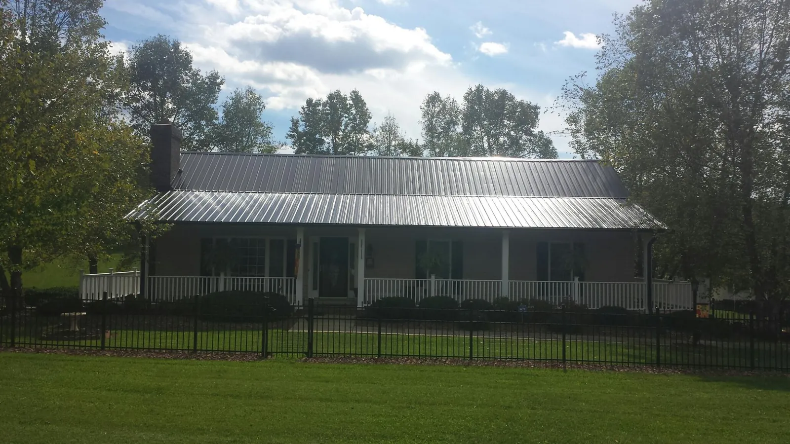 Gray metal roof on a brick ranch with a full width front porch — Gutter Guard Installation work by our crew in Elmhurst